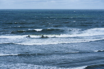 Stormy waves of the Baltic Sea with white crests off the coast of Estonia. Cloudy sky, dramatic landscape.