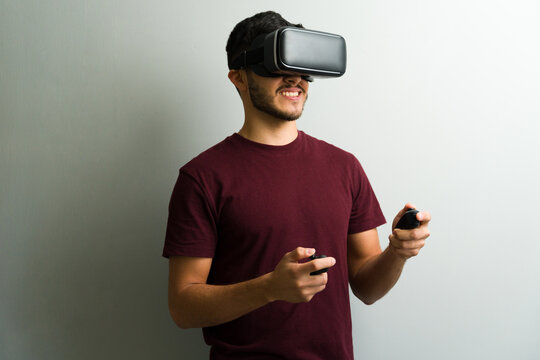 Portrait of a young man playing with virtual reality headset and controllers