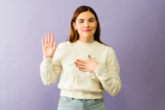 Young woman making an oath with hand on chest and raising hand