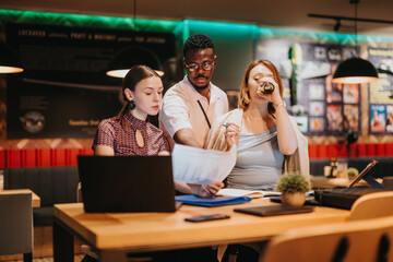 A diverse group of business professionals brainstorming and strategizing during a late night meeting, showing teamwork and collaboration. A modern workspace setting with focus on laptops and documents