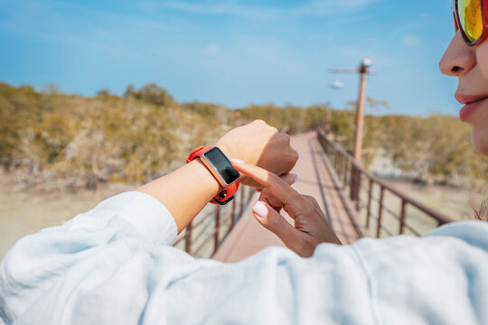 Person using a smartwatch on a bridge surrounded by nature, highlighting technology and outdoor exploration in a serene environment