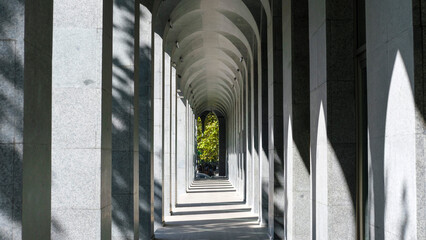 A modern architectural corridor with a series of stone arches creating a striking perspective