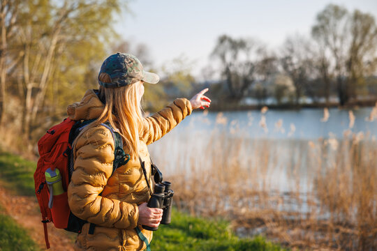 Ornithologist with binoculars searching water birds at lake. Bird watching in natural habitat