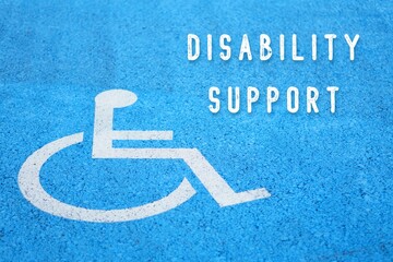 disability support. text written next to a disability icon on the asphalt. reserved parking with...