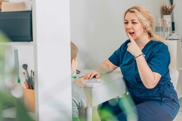 therapist demonstrating speech techniques to child in therapy session, engaging and instructive in bright clinic room - concept of speech therapy, educational support, child development