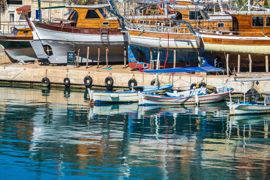 Traditional wooden gulet yachts dry docked for maintenance alongside small fishing boats in a harbor, Turkey