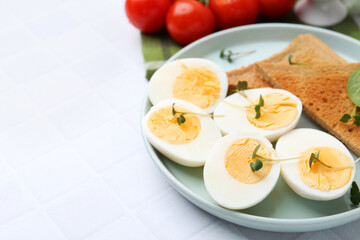 Cut hard boiled eggs with bread on white tiled table, closeup. Space for text
