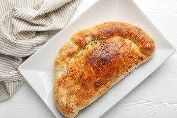 Delicious fresh calzone pizza on white wooden table, top view