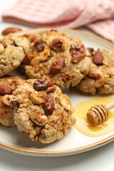 Tasty cookies with nuts and honey dipper on light table, closeup