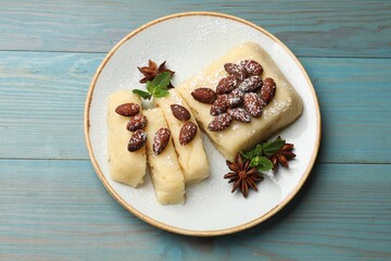Delicious sweet semolina halva with almonds, spices and mint on light blue wooden table, top view