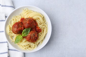 Delicious pasta with meatballs in bowl on light table, top view. Space for text