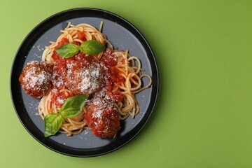 Delicious pasta with meatballs, basil and cheese on green table, top view. Space for text