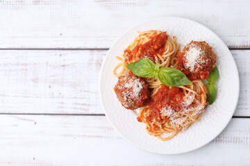 Delicious pasta with meatballs, cheese and basil on light wooden table, top view. Space for text