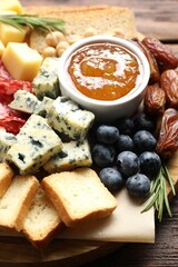 Different types of delicious cheese and other snacks on wooden table, closeup