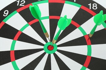 Dart board with green arrows on white background, closeup