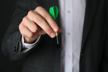 Fototapeta premium Man holding dart on black background, closeup