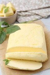Cut brick of butter and basil on white table, closeup