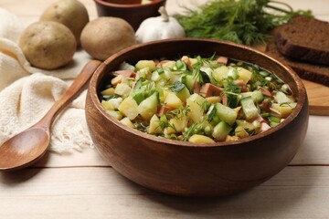 Delicious okroshka soup with kvass and ingredients on white wooden table, closeup