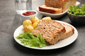 Delicious baked turkey meatloaf with potatoes served on grey table, closeup