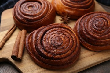 Delicious cinnamon rolls and spices on wooden table, closeup