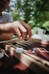 Relaxing outdoor backgammon game with dice and wooden board in sunlit setting, capturing strategic play and leisure