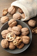 Fresh walnuts in bowl and bag on wooden table, flat lay