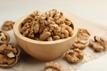 Peeled walnuts in bowl on light table, closeup