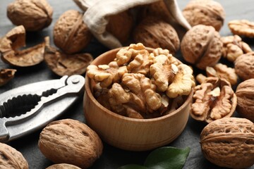 Fresh ripe walnuts, shells and nutcracker on table, closeup