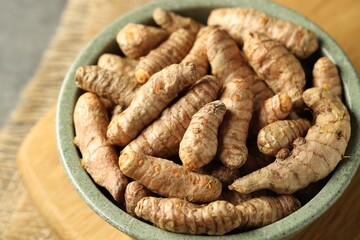 Tumeric rhizomes in bowl on grey table, closeup