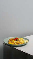 A plate of fried noodles served with egg and fried tofu. Topped with red and green chilies.