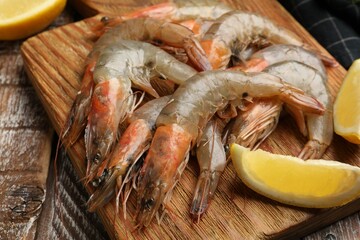 Fresh raw shrimps and lemon on wooden table, closeup