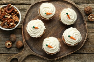 Delicious carrot cupcakes and walnuts on wooden table, flat lay