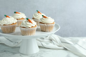 Delicious carrot cupcakes on white marble table against grey background, closeup