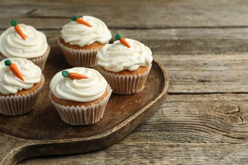Delicious carrot cupcakes on wooden table, closeup. Space for text