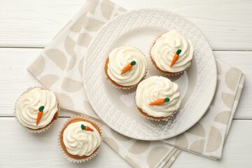 Tasty carrot muffins with cream on white wooden table, flat lay