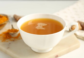 Aromatic turmeric tea, powder and rhizomes on white table, closeup