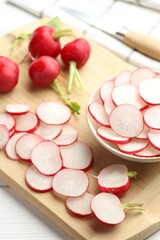 Fresh whole and cut radishes on white wooden table, above view