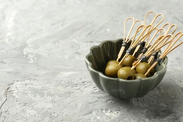 Tasty marinated olives on grey textured table, closeup. Space for text