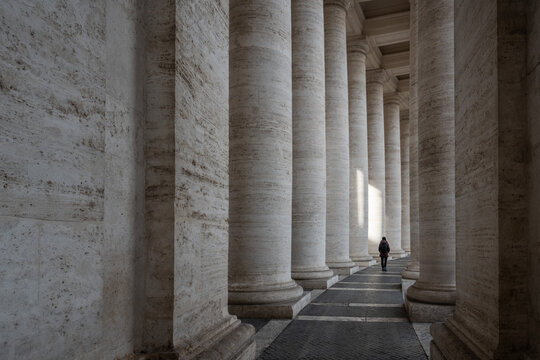 Donna da sola che cammina nel colonnato di San Pietro a Roma