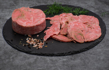 Vegan ham made of wheat gluten, shaped and cooked in a ham press. Sliced, slate board.