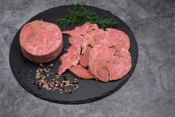 Vegan ham made of wheat gluten, shaped and cooked in a ham press. Sliced, slate board.