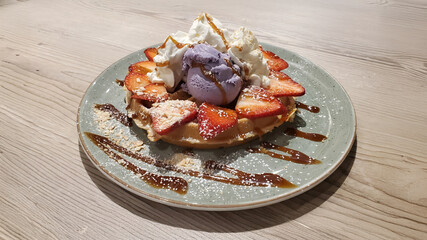 Waffle, ube and coconut ice cream, whipped cream, strawberries, caramel drizzles