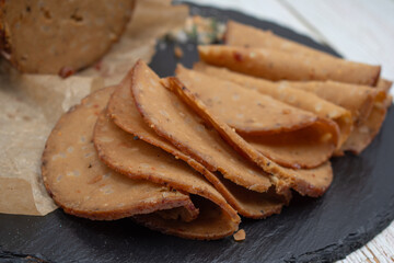 Seitan shaped and cooked in ham press, sliced on slate board. Vegan protein, plant based alternative to meat.
