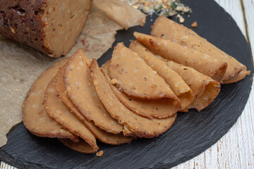 Seitan shaped and cooked in ham press, sliced on slate board. Vegan protein, plant based alternative to meat.
