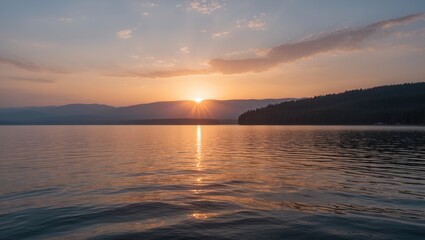 Naklejka premium Sunrise over calm lake reflecting mountains and trees with golden hues and gentle ripples on water Copy Space