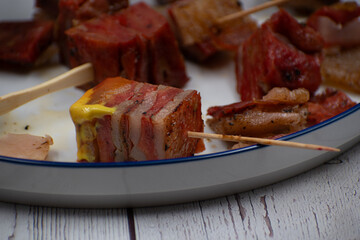 Vegan seitan pork belly appetizer, white plate, wooden table