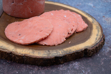 Vegan ham made of wheat gluten, shaped and cooked in a ham press. Sliced, wooden board.