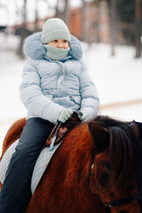 Young girl riding horse outdoors in winter wonderland