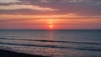 Sunset over calm waters with gentle waves reflecting vibrant colors in the sky and sandy beach in the foreground Copy Space