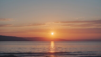 Sunset over calm ocean waters with reflections on the surface and soft clouds in the sky against a gradient of warm colors Copy Space